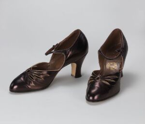  A pair of vintage high-heeled chocolate-brown leather women's shoes with decorative cut-out patterns on the vamps, presented side by side against a neutral background.