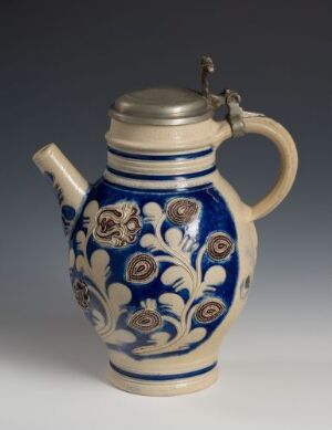  A traditional German ceramic stein with a pewter lid, featuring a deep cobalt blue floral pattern on a white background.