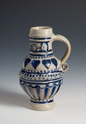  A traditional European-style ceramic jug with a bulbous body and slender neck, decorated with blue floral and geometric patterns on a white background, against a neutral grey backdrop.