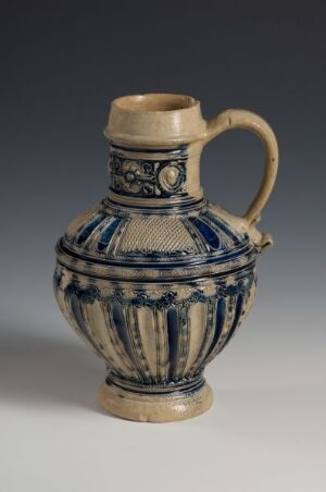  An ornate, globular ceramic jug with blue patterns on a cream background, featuring a single handle and a modestly flared neck, set against a gray backdrop.