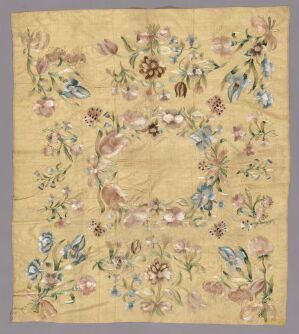  An embroidered fabric with a warm beige background, showcasing an intricate, multi-colored floral pattern with a less densely embroidered open circle in the center, creating a delicate garden-like appearance. Artist name and title are unknown.