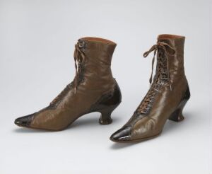  A pair of vintage women's ankle boots made of glossy chocolate brown leather with darker brown toe caps and heels, featuring small eyelets with darker brown laces, set against a light grey background.