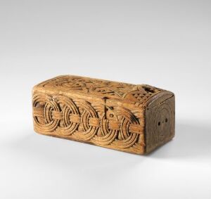  An intricately carved, rectangular wooden box with a warm honey-brown tone, set against a light neutral background. The detailed craftsmanship suggests historical significance or artistic reproduction. Artistname and title are unknown.