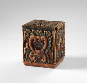  A carved wooden cube with intricate foliate patterns on a light grey background, displaying detailed craftsmanship in a dark brown wood. Artist name and title are unknown.