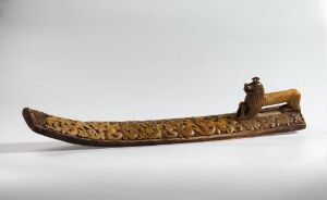  An ornate wooden sled with detailed golden carvings on a neutral gray background, showcasing a blend of craftsmanship and aesthetic design.