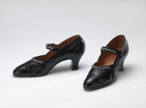  A pair of vintage black leather women's shoes with pointed toes, low wide heels, and a decorative studded strap across the instep, displayed on a light-gray background.