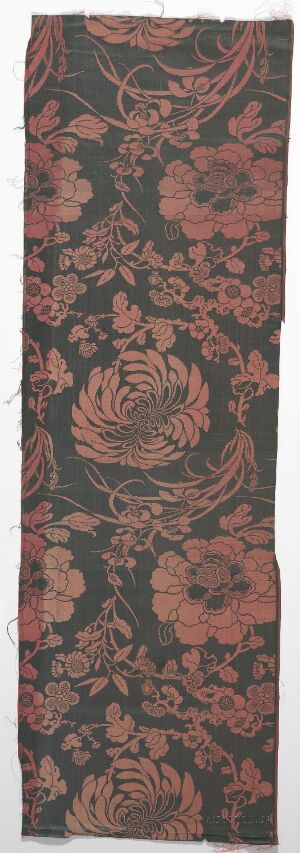  A vertical textile with a detailed floral pattern against a dark, blackish-green background. The design features a large central flower in deep red and pink hues, surrounded by smaller blooms and foliage in complementary colors with cream outlines.