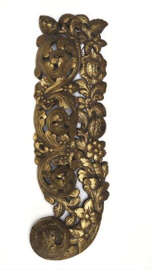  An elongated, ornamental, and possibly antique wall-mounted piece with a design featuring stylized leaves and floral motifs in a golden brown color, suggesting an aged bronze material, set against a plain white background. The artist's name and title of the work are unknown.