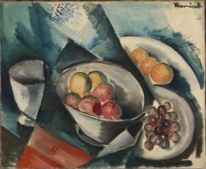  An oil painting on canvas titled "Stilleben" by Maurice de Vlaminck, depicting a vibrant still life scene with a bowl of mixed fruit, a dish of grapes, and a white cup set against a backdrop of angular, blue-toned shapes suggestive of folded fabric, accented by patches of white for reflected light and a prominent red stripe on the lower left.