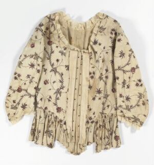  A vintage-style blouse with a cream or light beige base featuring a delicate floral and botanical pattern in muted brown or maroon tones, with billowy sleeves and vertical ruffle details, presented on a neutral background. Artistname and title are unknown.