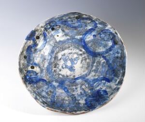  A handcrafted ceramic dish by Marit Tingleff from the "Blue Dishes" series, featuring a spectrum of blue tones with splotches and speckles, a glossy glaze, and subtle earthy undertones in the less decorated center.