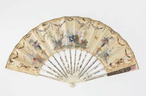  An antique handheld folding fan displayed open, with a cream-colored background adorned with a pastoral scene in muted colors, featuring tiny human figures in historical clothing, trees, flowers, and a lace-like scalloped edge.