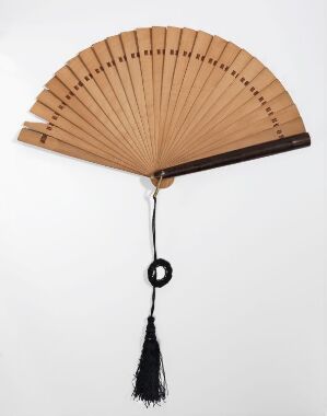  A traditional beige handheld folding fan with wooden rods, fully extended to display its curve, featuring a black tassel hanging from the bottom pivot point. Artistname and title are unknown.