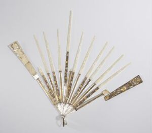  An antique ivory or bone folding fan with gold-colored decorations, fully opened, against a light grey background.