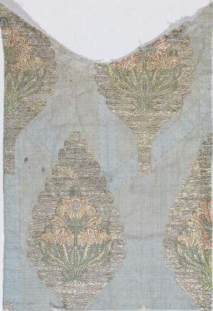  An antique piece of semi-sheer fabric with a muted earth-tone pattern featuring symmetrical ornate motifs of greens, dusty rose, and gold, showing elaborate craftsmanship with a "V" shaped neckline, suggesting historical fashion or decorative use.