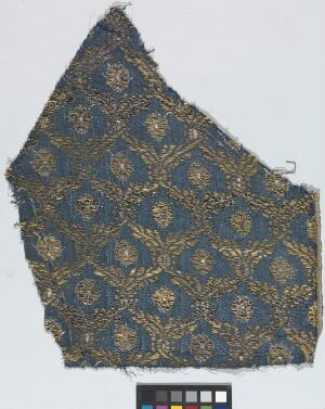  Antique fragment of navy blue fabric with golden ornate pattern and a color scale at the bottom.