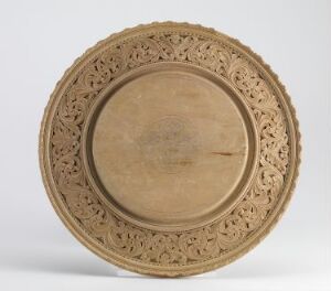  A shallow, carved wooden dish with an intricate lace-like border and a plain, smooth center, displaying the natural grain of the wood.