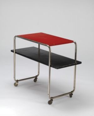  A two-tiered serving cart by Josef Kussius Metallvarefabrikk with a shiny metal frame, featuring a bright red upper shelf and black lower shelf, set on four small wheels against a grey background.