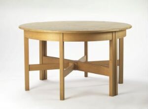  Round wooden table with a smooth, honey-toned finish, supported by four tapering legs connected by a crossbeam, set against a plain white background.