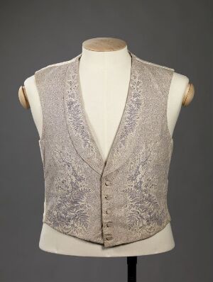 
 A pale grey waistcoat with intricate darker grey embroidery on a mannequin torso against a neutral grey background.