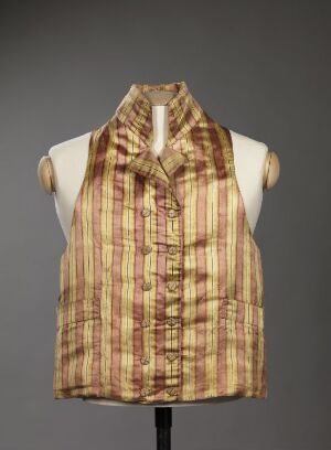  A sleeveless plaid garment in beige, dark brown, and reddish-orange tones displayed on a white torso mannequin against a mid-gray background.