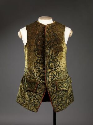  An antique olive green and gold brocade vest with intricate floral and acanthus leaf patterns displayed on a mannequin against a dark background.