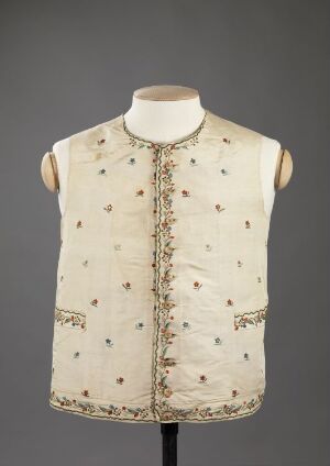  Antique sleeveless vest with high neckline and floral patterns in pale blue, pink, and golden accents on a creamy white fabric, displayed on a mannequin against a gray background. Artist name and title unknown.