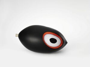  A sleek black glass sculpture titled "Skulptur m/øye" by Tuva Gonsholt, depicting an eye with an orange, white and black concentric design on a neutral background, showcasing the technique of blown and polished overlay glass.