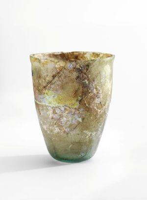  A handcrafted glass vessel with a tapered shape, featuring a blend of translucent green at the top, yellow-ocher in the middle, a ring of opal-like white, and murky green towards the base, set against a white background. Artist's name and title are unknown.