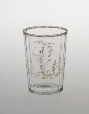 
 A clear glass tumbler with delicate gold vine patterns ascending from the base, set against a light grey background.