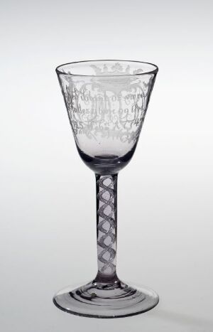  A clear glass goblet with an etched lattice pattern on the bowl and a faceted spiral stem, set against a light grey background. Artistand title are unknown.