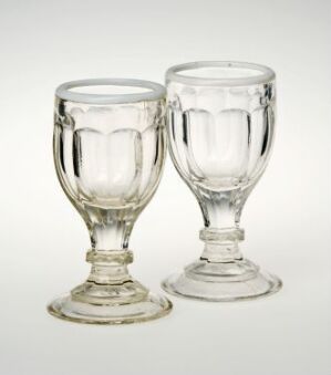  Two transparent glass goblets with textured designs standing on a white background.