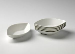  A set of elegant white porcelain dishes, one tilted on the left and a neat stack of dishes on the right, displayed on a light-grey background.