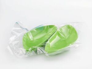  Two lime green dishes made from molded bioplastic and sugarcane fibers by artist Anne Bannick, sealed in transparent vacuum-packed plastic, against a white background. The color intensity and environmentally friendly materials highlight a modern, sustainable design.