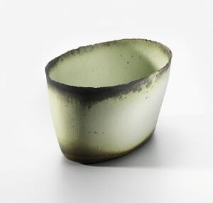  "Liten lys grønn oval," a small, light green oval porcelain bowl with a darker, almost black-rimmed edge, exhibiting a smooth gradient glaze. Created by artist Sidsel Hanum, this handcrafted ceramic piece merges function with a serene and organic aesthetic.