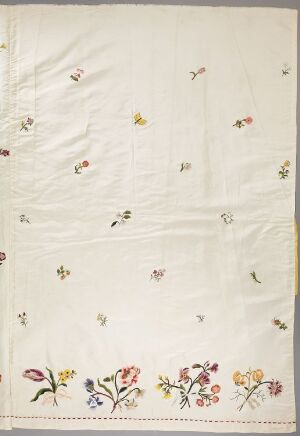  An off-white textile featuring scattered, multi-colored floral embroidery or print designs, with denser, larger floral patterns toward the bottom.