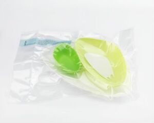  "Disposable" by Anne Bannick - A set of eco-friendly disposable tableware including a lime green plate, a lemon yellow bowl, and a white spoon, all vacuum-packed in a clear plastic bag, emphasizing sustainable design and materials.