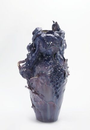 
 A glossy, deep blue ceramic sculpture with organic shapes and textures, varying from dark blue to light lavender, set against a plain white background.