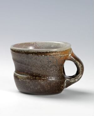  A handcrafted ceramic coffee mug with a gradient of earthy browns, ranging from dark chocolate at the base to creamy beige at the rim, featuring a sturdy handle and a reflective, glossy finish.