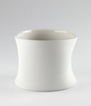  A white porcelain pitcher designed by Margit Seland, titled "Pinched Pitcher," with a unique asymmetrical shape resembling a gentle pinch on two sides, set against a neutral gray background.