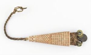  An intricately carved light tan sheath with a geometric pattern, featuring golden decorative metalwork with dark accents at one end and an attached braided dark cord, displayed against a white background.