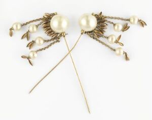  A pair of vintage gold-toned brooches with a central large pearl and six smaller pearls on each, set in a leaf or wing-like arrangement, on an off-white background.