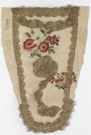  A vintage embroidered textile fragment with scalloped gold edges, featuring floral designs in shades of pink and green on a creamy beige background with signs of aging and wear.