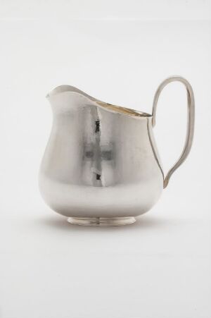  A polished silver creamer pitcher with a sleek design and reflective surface on a white background.