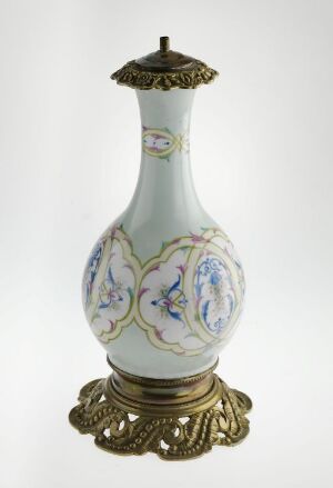  An ornate porcelain vase with a brass base and top, featuring pastel blue background and hand-painted floral designs with touches of gilding.