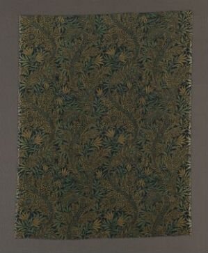  A textile designed by Turnbull & Stockdale titled "Conventional Foliage." The art piece is a cotton fabric with a dark brown background featuring a complex pattern of intertwined leaf motifs in shades of dark and light green with subtle touches of blue and gold, exemplifying the technique of weft pile weaving with a printed pattern.