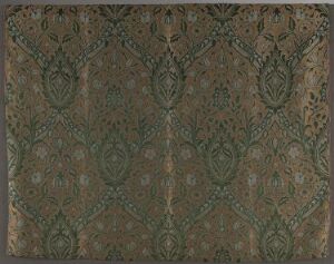  A fabric titled "Persian Brocatel" by Morris & Co, displaying intricate Persian-inspired patterns in shades of brown, green, gold, and possibly blue, with elaborate diamond shapes and floral motifs set against a muted earthy-toned background. The textile demonstrates elaborate handwoven artistry combining silk and wool with a secondary linen lining.