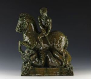  Ceramic sculpture "St. Georg og dragen" by Sigri Welhaven, depicting Saint George mounted on a rearing horse battling a dragon beneath them. The sculpture is dark green with a glossy finish and textured details, showcasing the figures in mid-action.