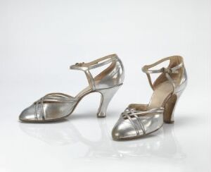  A pair of silver metallic high-heeled shoes with slender heels and peep-toe design set against a white background.