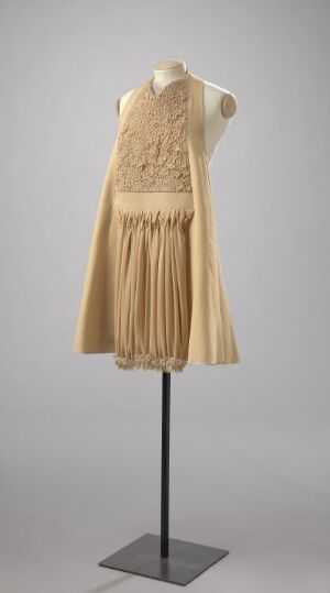  A knee-length, sleeveless, creamy beige dress with floral lace bodice displayed on a headless and armless mannequin against a neutral gray background.